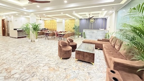 A spacious lobby with a marble floor, seating area with sofas and chairs, a reception desk, and ceiling fans. - The Prominence Hotel Greater Noida (Greater Noida)
