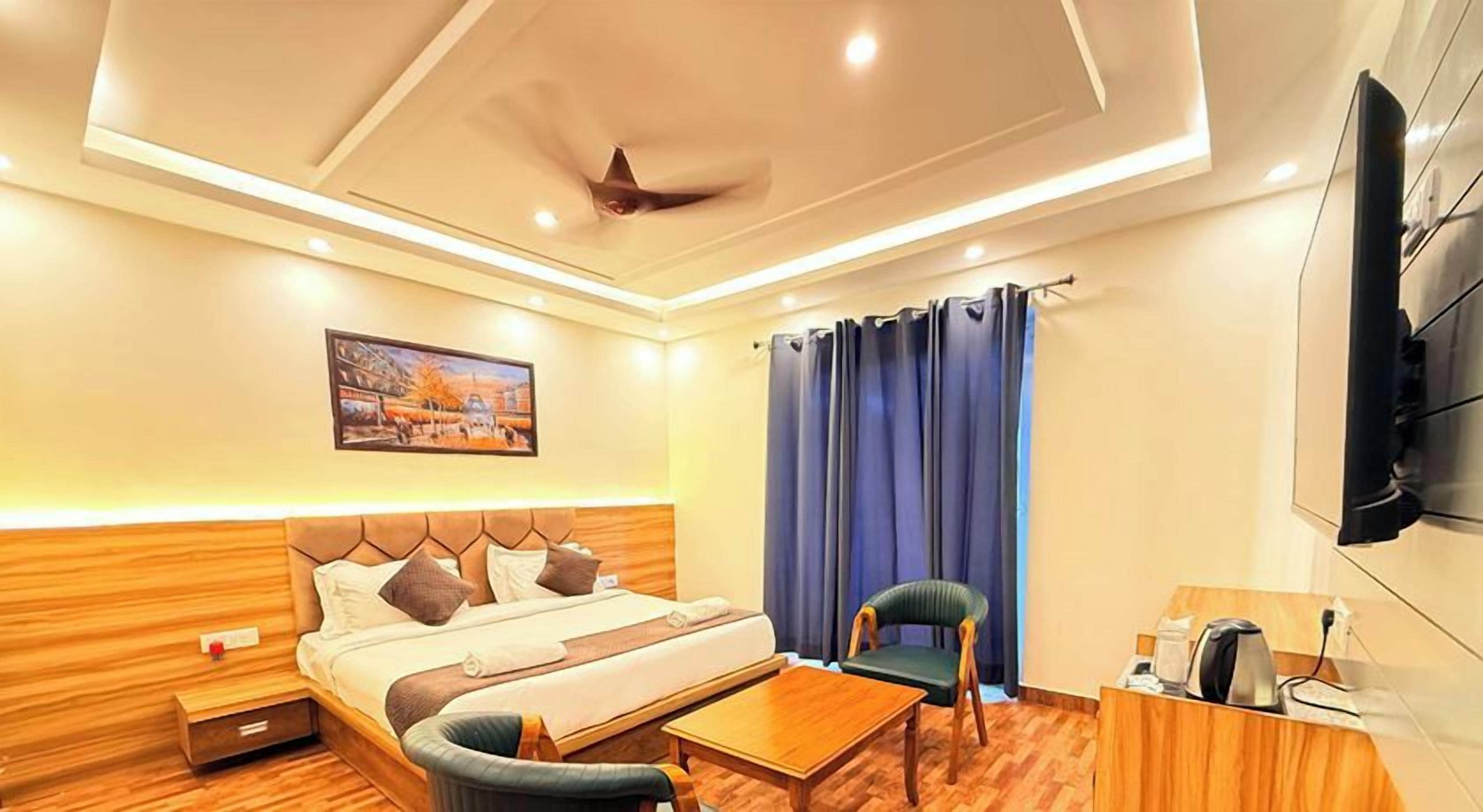 A hotel room with a bed, a desk, a chair, a television, and a ceiling fan.
