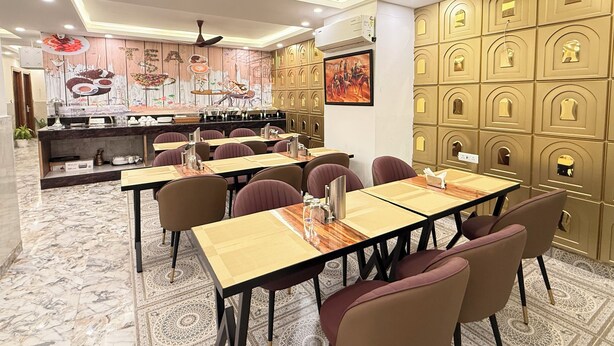 A restaurant with marble flooring, multiple tables with chairs, a counter with a menu, and decorative wall panels. - The Prominence Hotel Greater Noida (Greater Noida)