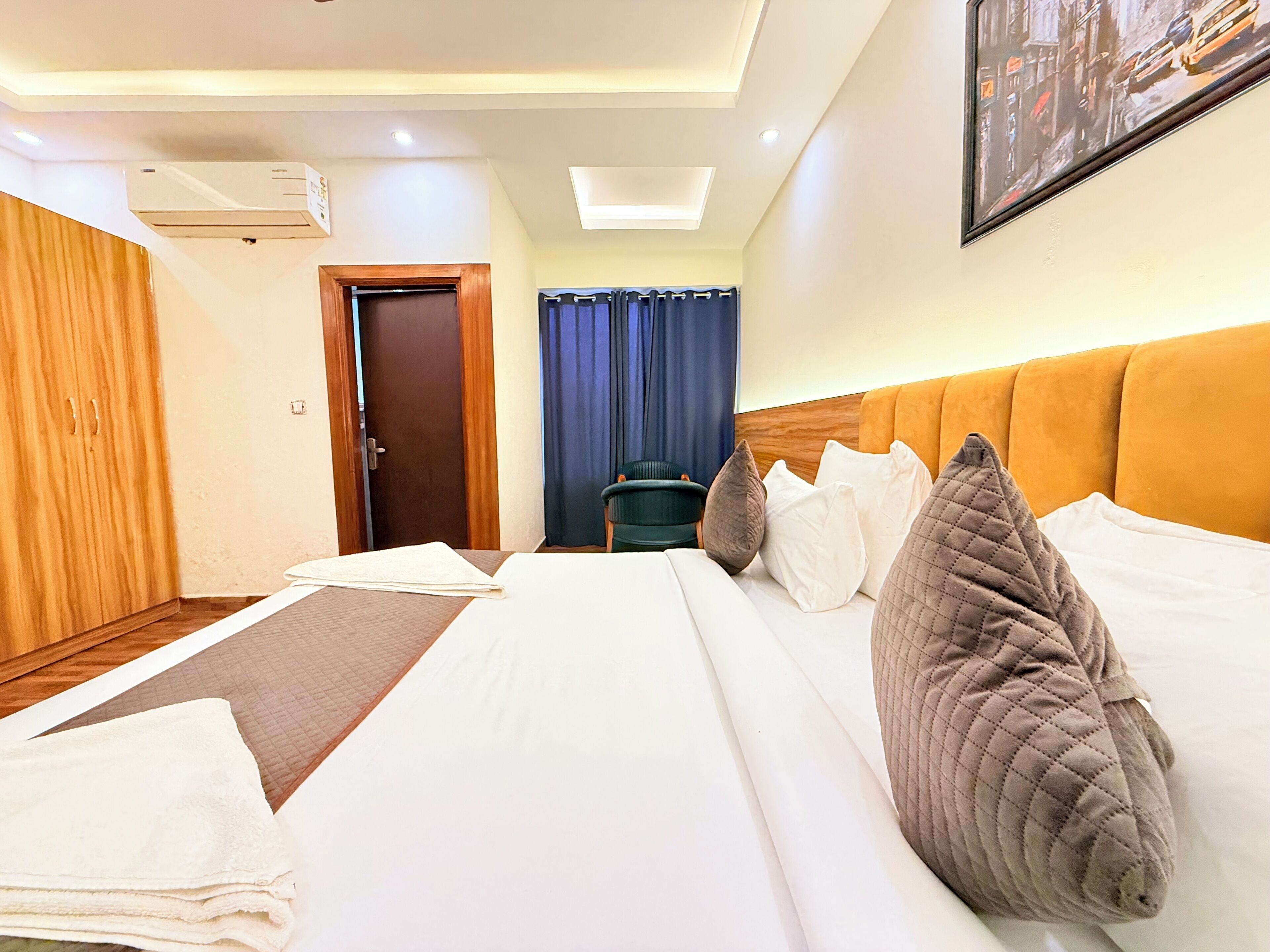 Een hotelkamer met een bed, een bureau, een stoel, een kledingkast en een airconditioning.