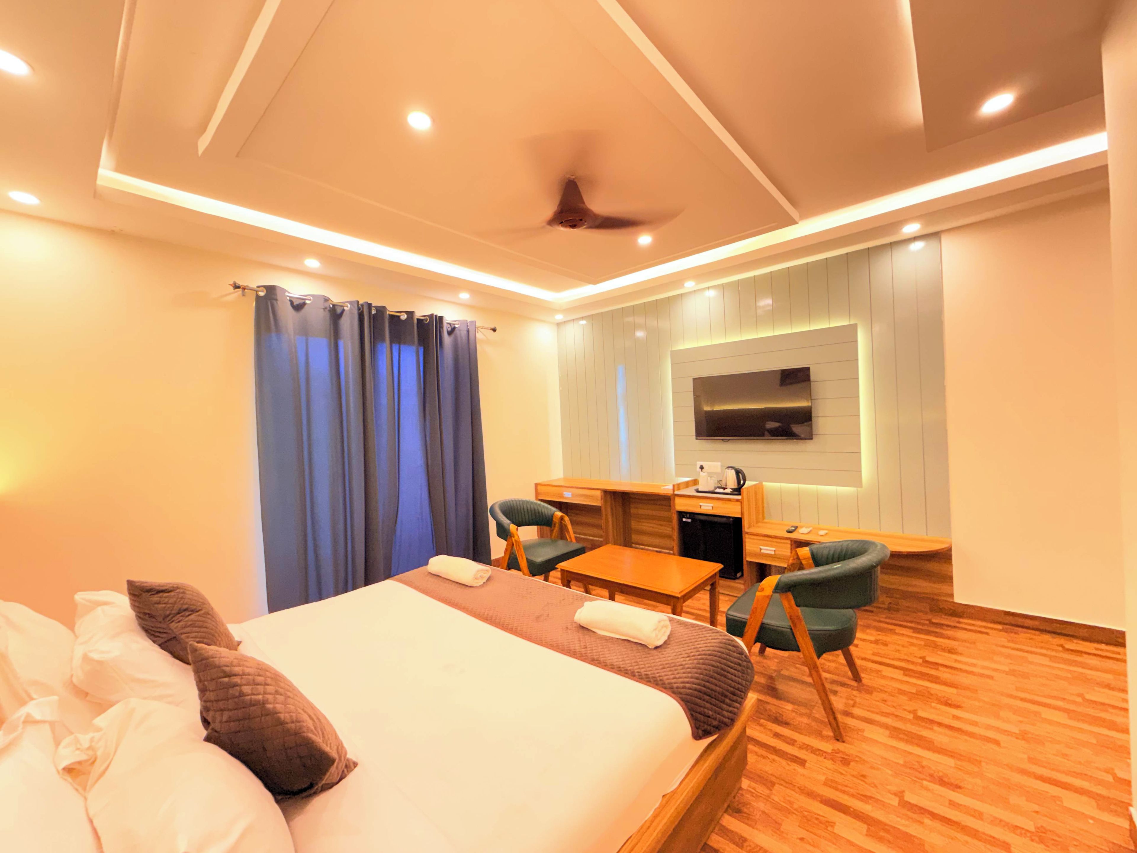 A hotel room with a bed, a desk, a chair, a television, and a ceiling fan.