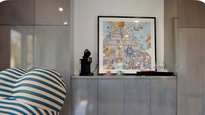 Et moderne interiør med et stort indrammet kunstværk, et slankt gråt skab og en stribet stol.