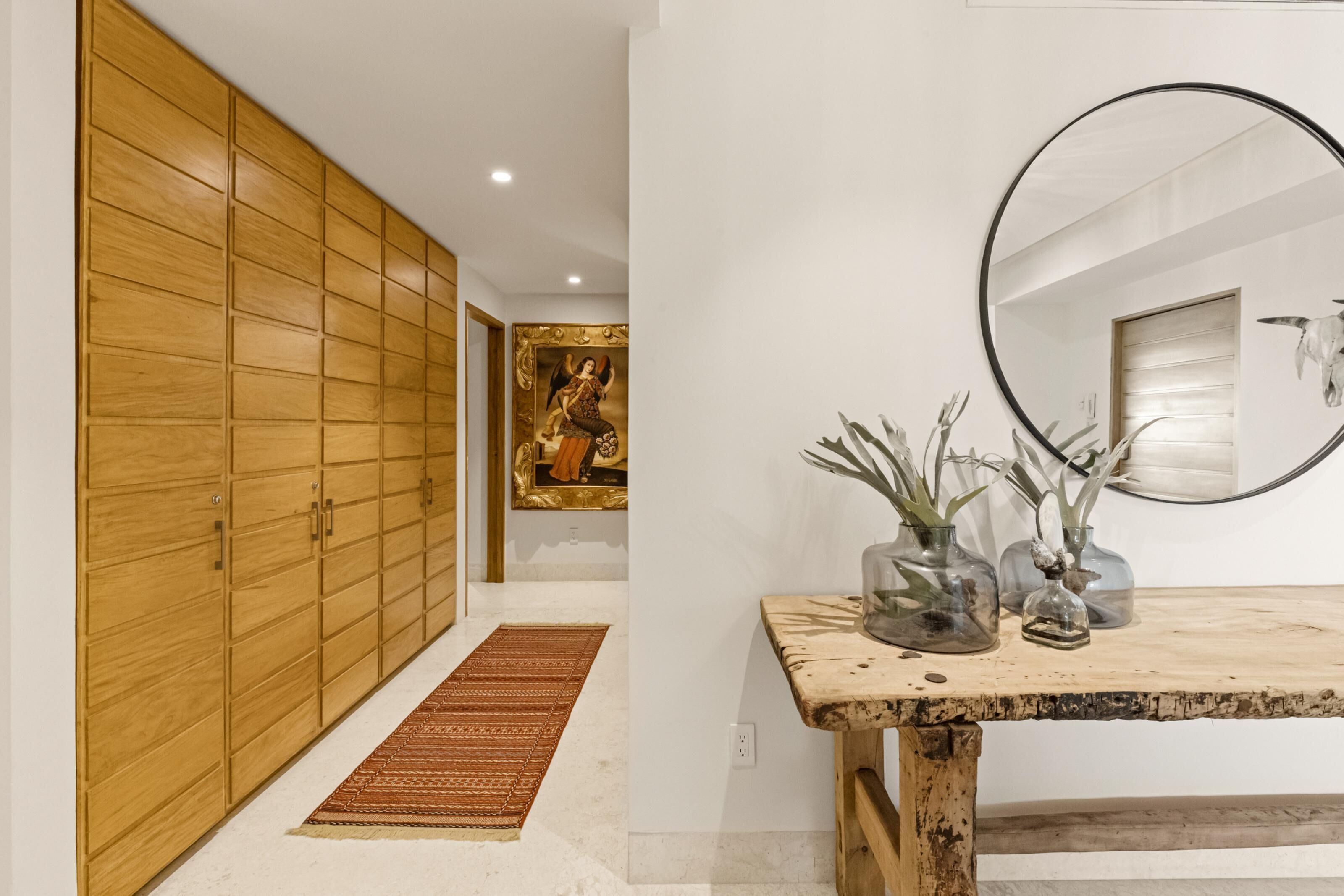 A hallway with wooden paneling, a patterned rug, and a framed artwork on the wall.