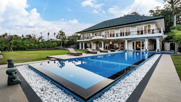 Een modern huis met een groot zwembad, buitenmeubilair en een verzorgde tuin.