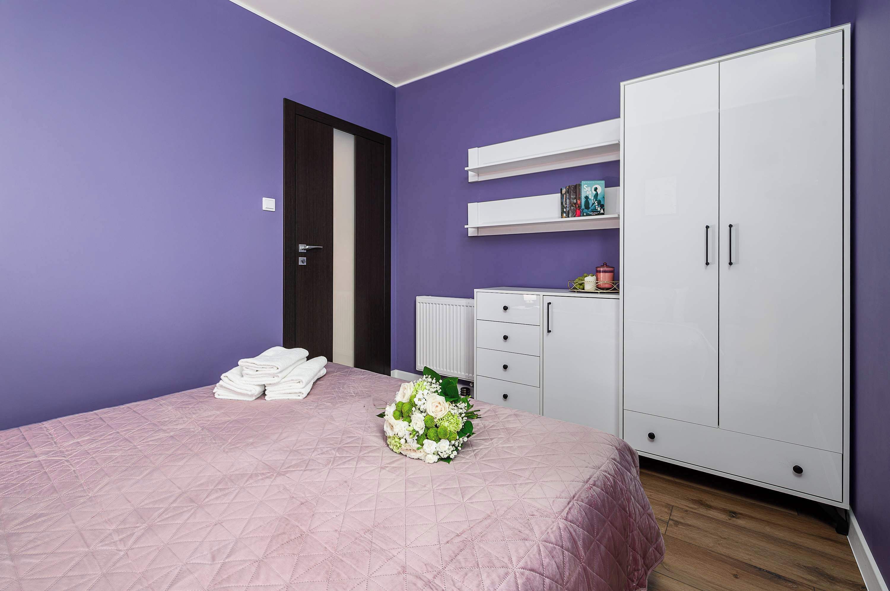 A bedroom with a bed, a wardrobe, and a small dresser.