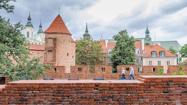 A brick wall with a tower and a church in the background. - Lumina Apartments for family in the Old Town (Warszawa BIG)