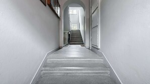 A narrow, white-walled hallway with a staircase leading to an upper floor. - Lumina Apartments for family in the Old Town (Warszawa BIG)