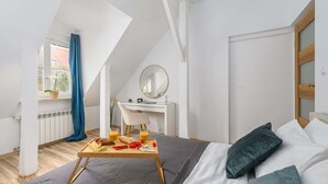 A modern bedroom with a bed, bedside table, and a desk with a chair. - Lumina Apartments for family in the Old Town (Warszawa BIG)
