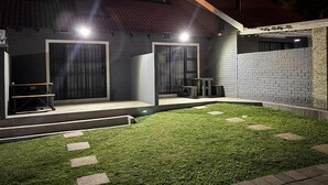 A modern house with a well-maintained lawn, a covered patio, and a brick exterior. - Rolem Guest House (Randburg)