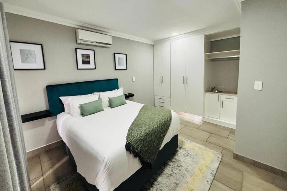 A bedroom with a bed, a wardrobe, and a small kitchenette.