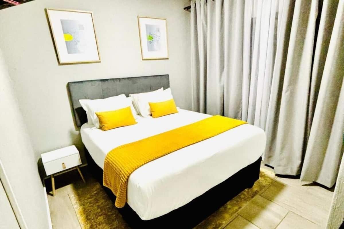 A hotel room with a bed, a nightstand, and two framed pictures on the wall.