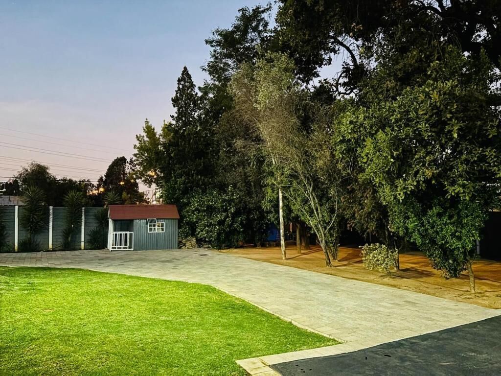 A backyard with a paved patio, a small shed, and a well-maintained lawn.
