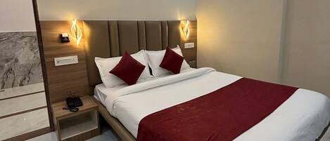A modern hotel room with a large bed, marble flooring, and built-in nightstands.