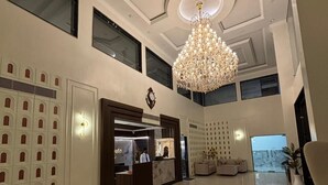 A spacious lobby with a high ceiling, a chandelier, a reception desk, and a seating area. - The Silk Route Resort (Chanderi)