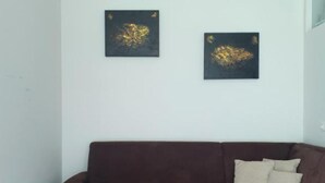 A living room with a brown sofa, a coffee table, and two abstract gold paintings on the wall. - Apartment HAL (Hinterstoder)