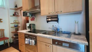 A compact kitchen with wooden cabinets, a built-in oven, a sink, and a coffee maker. - Apartment HAL (Hinterstoder)