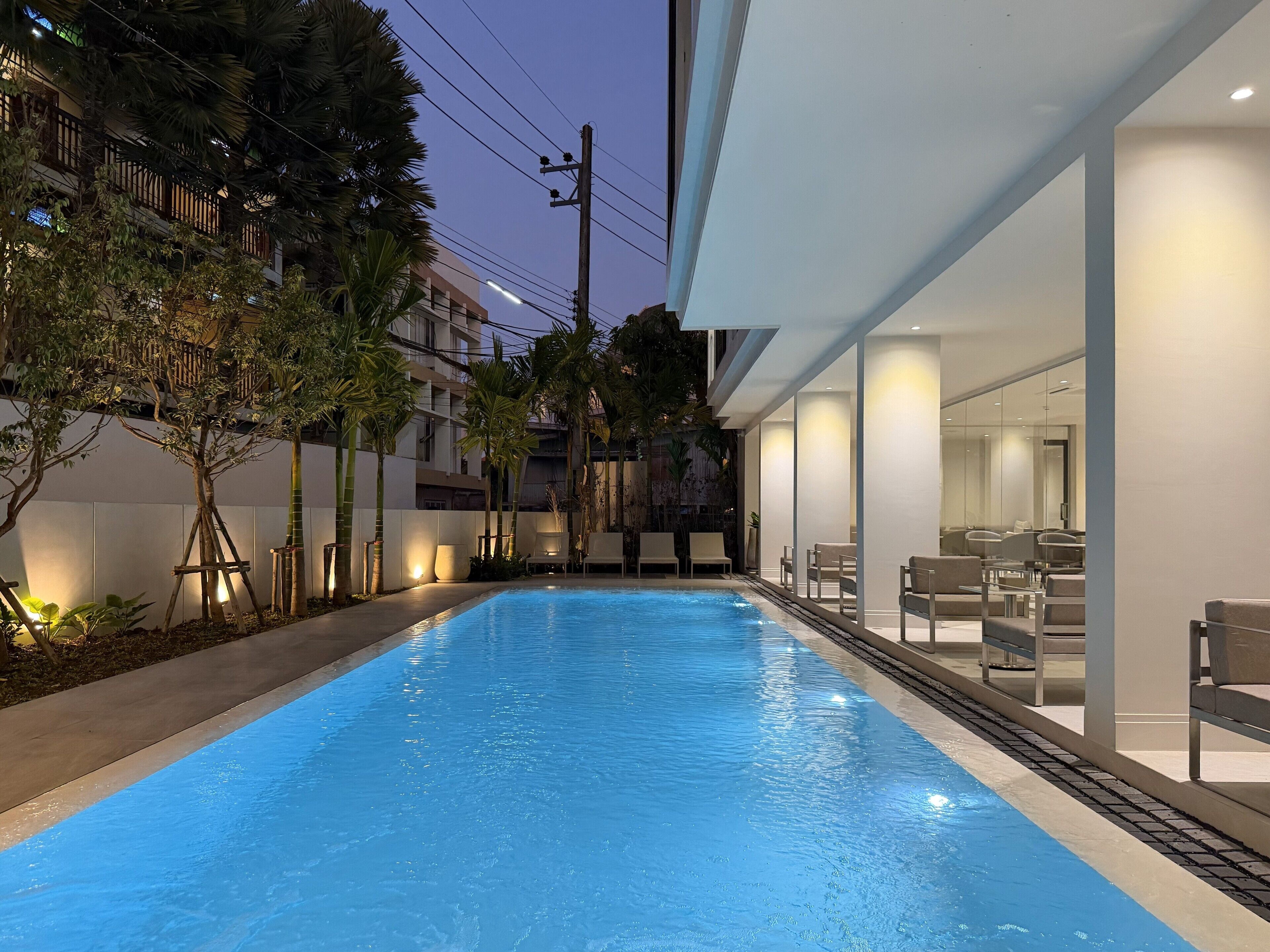 A swimming pool with lounge chairs and a building with large windows.