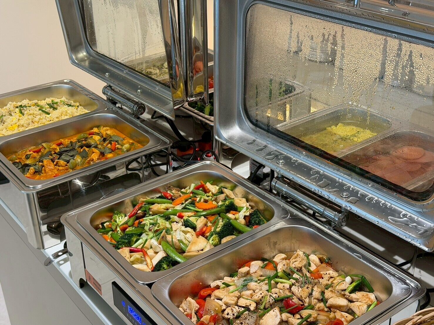 Un bufé con diversos platos, incluyendo arroz, pollo y verduras mixtas.