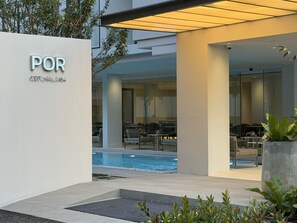 A modern hotel exterior with a pool, outdoor seating, and a sign reading "POR KOTOGASAP". - POR Kotchasarn (Chiang Mai)