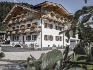 Ein mehrstöckiges Gebäude mit Balkonen, die mit Blumen geschmückt sind, einer Treppe zum Eingang und freiem Blick auf die Umgebung.
