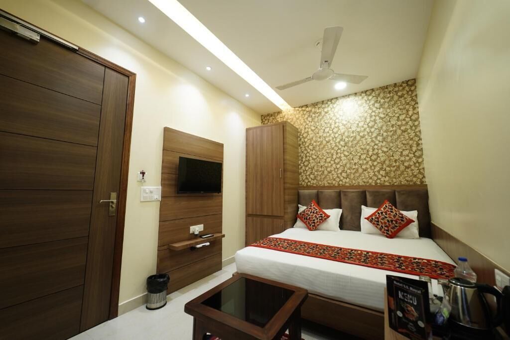 A bedroom with a bed, wardrobe, TV, and a small table.