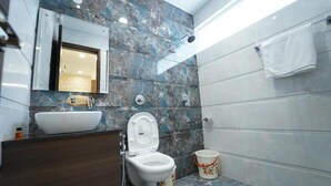 A bathroom with a marble backsplash, a white sink, a toilet, and a towel hanging on the wall. - Hotel SS Royal (Amritsar)