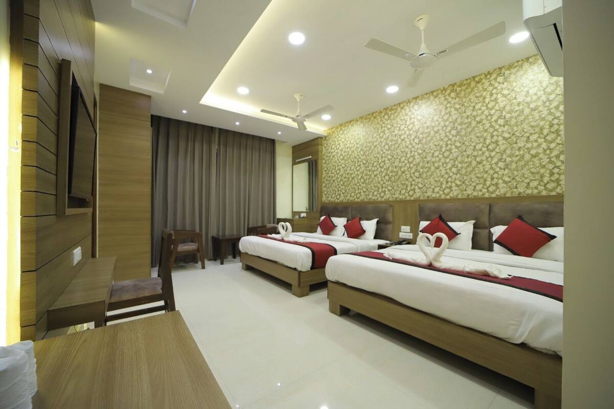 A hotel room with two beds, a desk, a chair, a ceiling fan, and a large mirror.