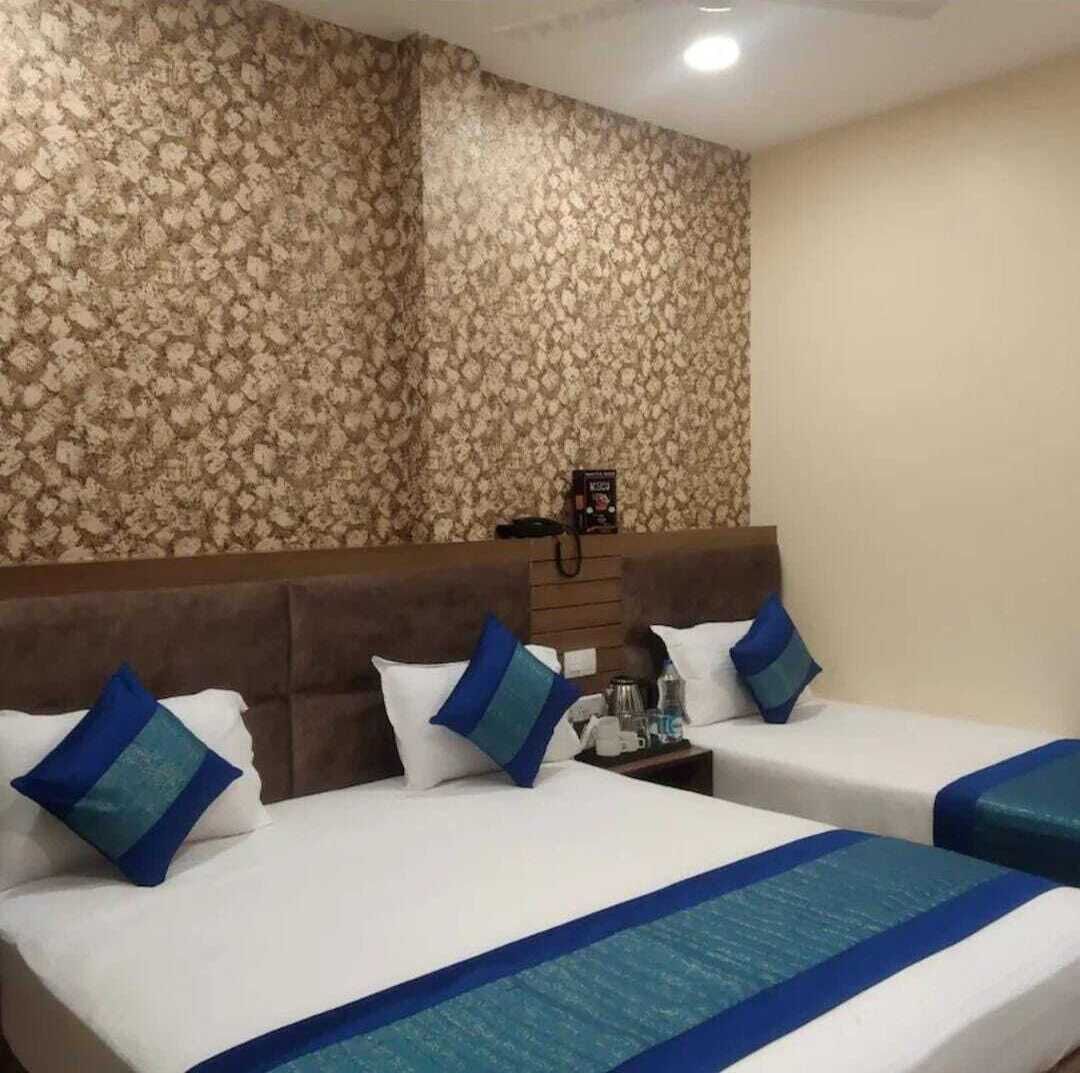 Una camera d'albergo con due letti, una testiera, un comodino e carta da parati decorata.