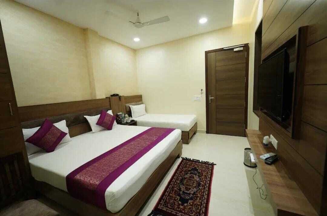 A hotel room with two beds, a TV, a desk, and a wardrobe.