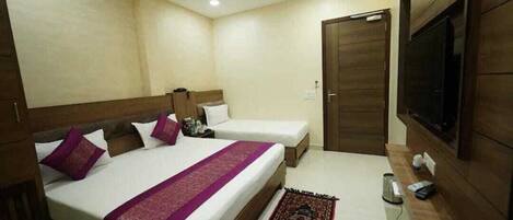 A hotel room with two beds, a TV, a desk, and a wardrobe.