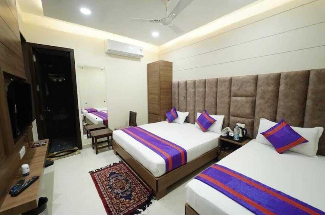 A hotel room with two beds, a TV, a desk, and a ceiling fan.