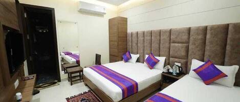A hotel room with two beds, a TV, a desk, and a ceiling fan.