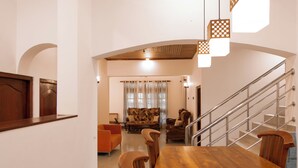 A spacious living area with a wooden dining table, a sofa, and a staircase with a metal railing. - Sand Cliff Villa (Galle)
