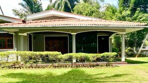 A house with a covered porch, a lawn, and tropical vegetation. - Sand Cliff Villa (Galle)