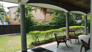 A covered outdoor area with a tiled floor, several wooden chairs, and a bench. - Sand Cliff Villa (Galle)