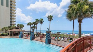 A pool area with a view of the beach and ocean, surrounded by palm trees and lounge chairs. - Beachfront Condo, Oceanview Balcony, Lagoon Pool | Thomas Dr #2308 by AvantStay (Panama City)