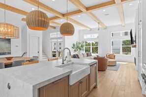 Een moderne keuken met een groot eiland, houten balken en hanglampen.