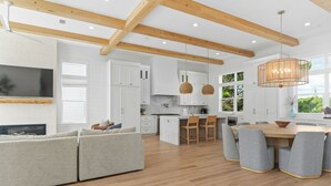 Una cocina moderna con armarios blancos, vigas de madera y una isla grande con asientos.