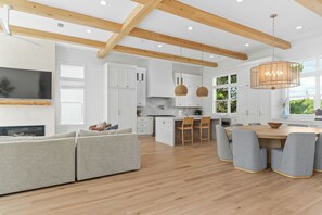 A modern kitchen with white cabinets, wooden beams, and a large island with seating. - 5BR Home by 30A with Bikes, Large Kitchen, Multiple Balconies & Beach Access (Inlet Beach)