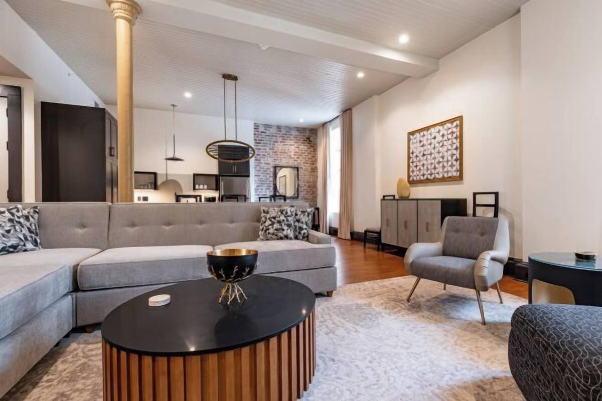 A modern living room with a sectional sofa, a round coffee table, a grey armchair, and a patterned rug.