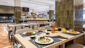 Un restaurant doté d’un espace buffet, de tables où sont disposés des plats et d’une bouteille de vin Cesta Moscana.