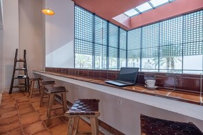 Une cuisine avec un long comptoir, un ordinateur portable et des tabourets.