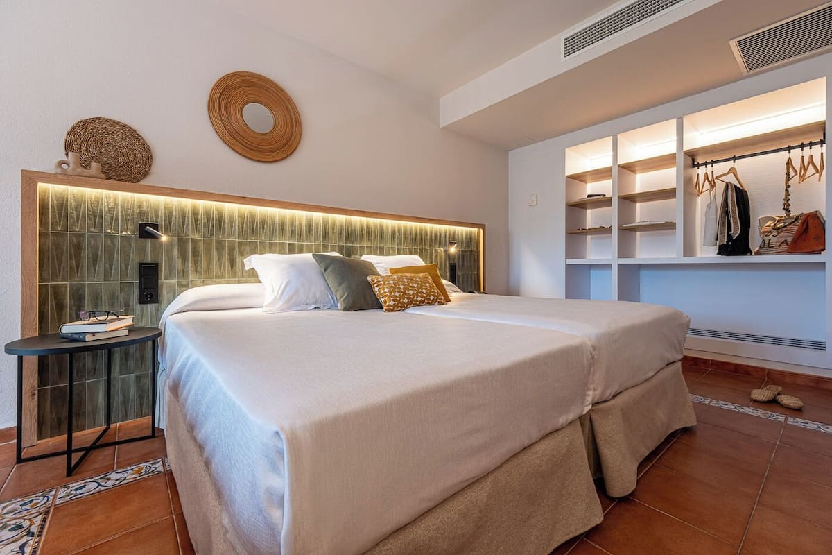 A double bed with a headboard, bedside tables, and a wardrobe with hanging space.