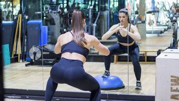 Un gimnasio con equipo de ejercicio, un espejo y piso de madera.
