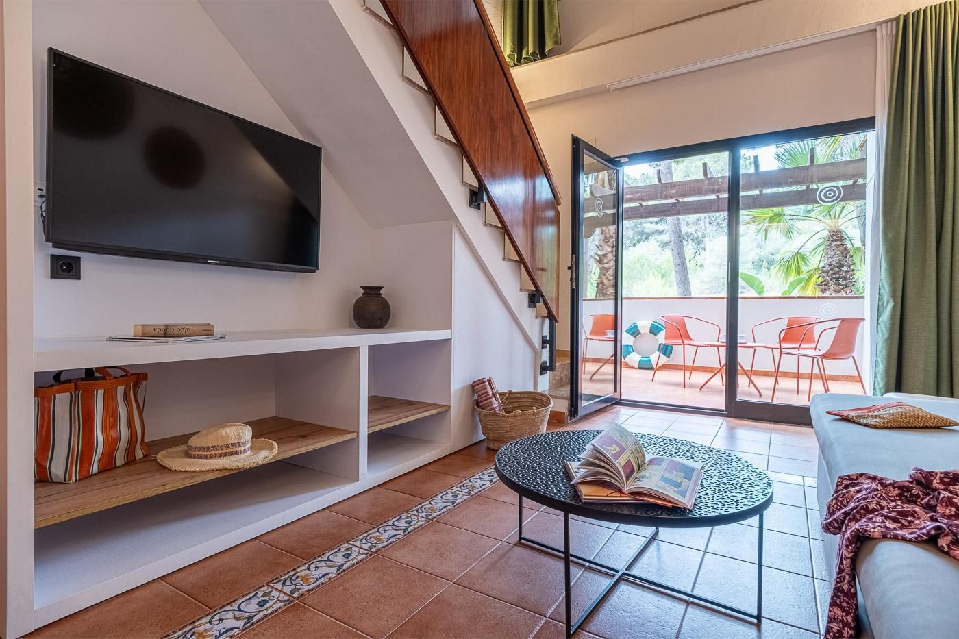 Una sala de estar moderna con una televisión de pantalla plana, una estantería, una mesa de centro y un sofá.