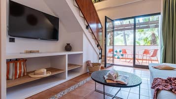 Una sala de estar moderna con una televisión de pantalla plana, una estantería, una mesa de centro y un sofá.
