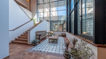 Zona interior espaiosa amb escala, un banc de fusta i plantes en testos.