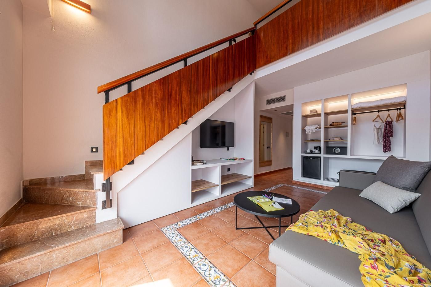 Una sala de estar moderna con una escalera, un sofá, una mesa de centro y un televisor.