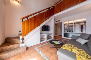 Una sala de estar moderna con una escalera, un sofá, una mesa de centro y un televisor.