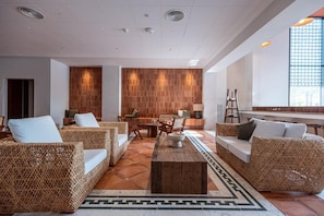 Un área de estar moderna con muebles de mimbre, una mesa de centro y un suelo estampado.